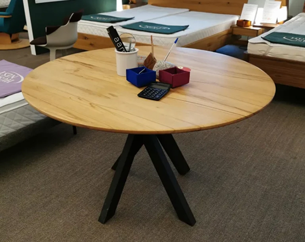 Runder Holztisch mit schwarzem Kreuzgestell in einem Möbelgeschäft