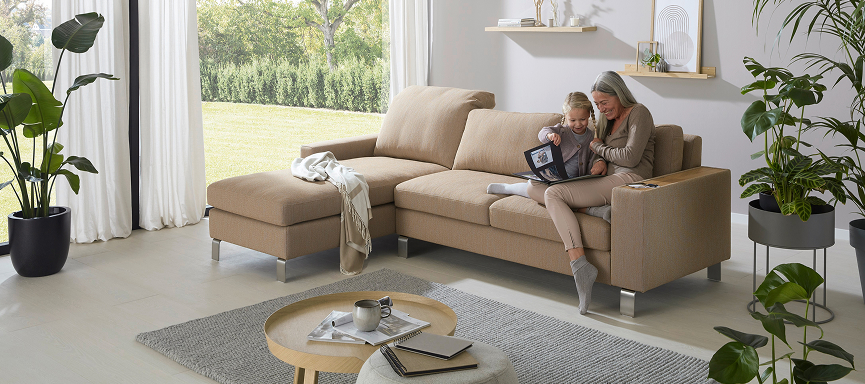 Familie sitzt gemeinsam auf Sofa im modern eingerichteten Wohnzimmer